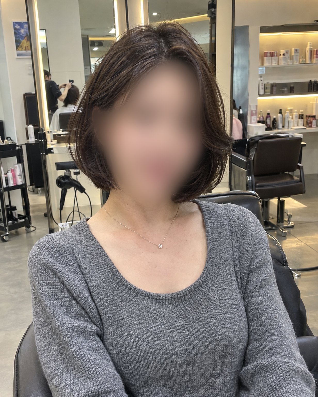 어깨 위로 떨어지는 레이어드 단발을 한 여성의 미용실 원본 사진(얼굴 블러 처리)